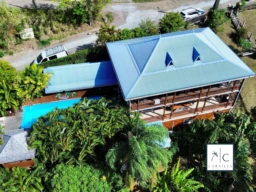 Belle maison avec une grande terrasse et une piscine, entourée d'une végétation luxuriante.