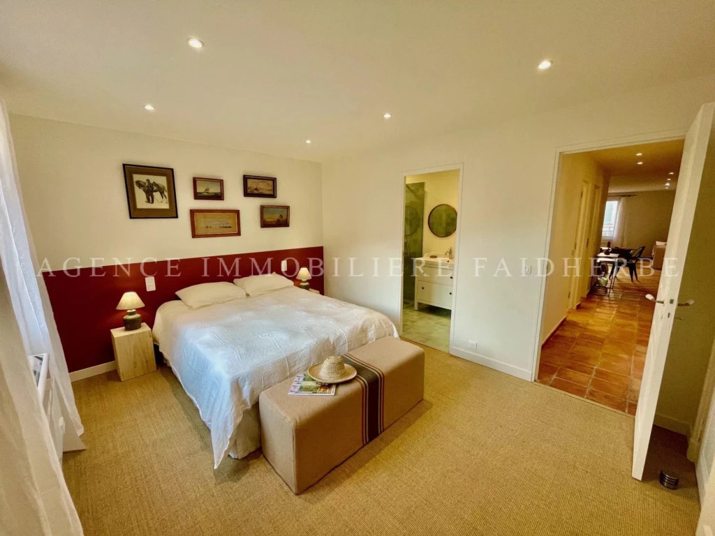 Chambre lumineuse avec un grand lit et décoration élégante.