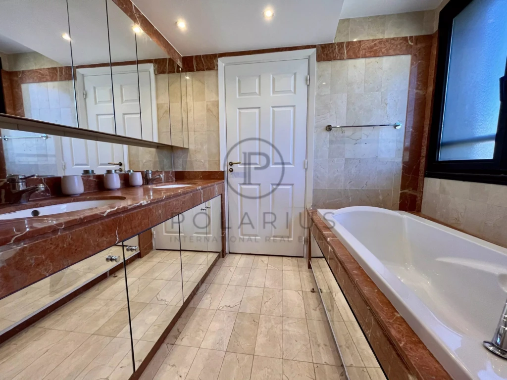 Salle de bain spacieuse avec baignoire et grand miroir.