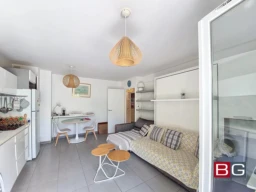Salon lumineux avec canapé et cuisine ouverte dans un appartement confortable.