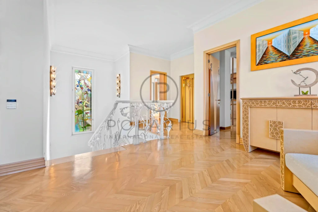 Un intérieur élégant avec un sol en bois, des murs clairs et un tableau coloré. Une rampe en métal blanc ajoute une touche artistique.
