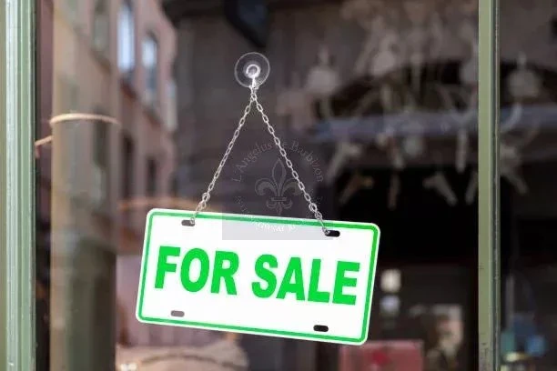 Close-up on an green sign in a window with written in it "For sale".