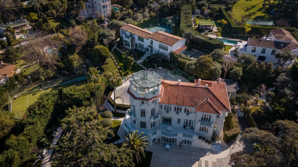 Grande villa élégante entourée de jardins luxuriants dans un cadre verdoyant.