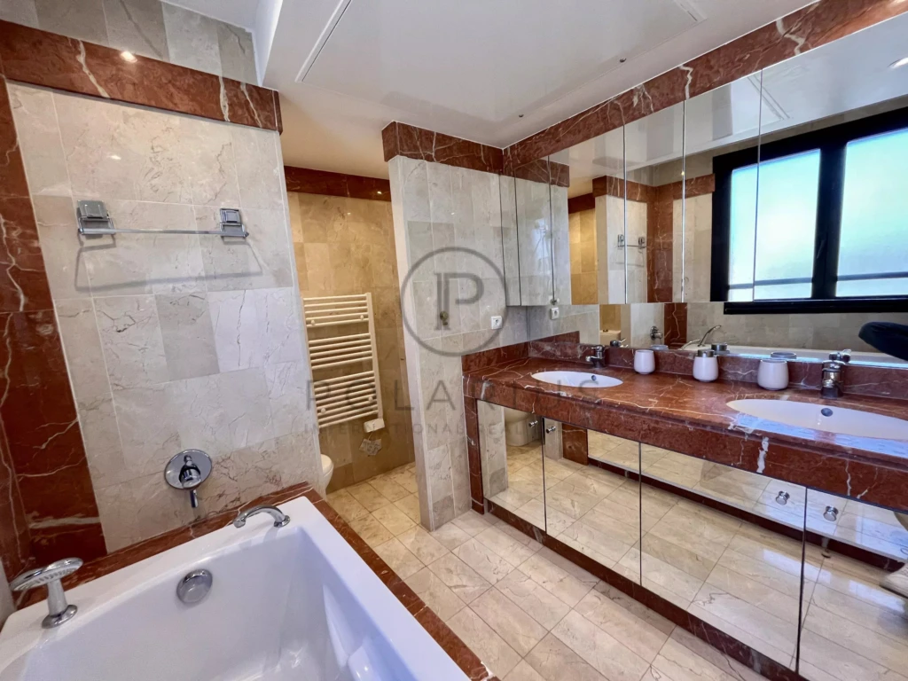 Salle de bain lumineuse avec baignoire et grand lavabo.