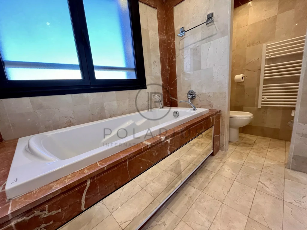 Salle de bain moderne avec baignoire en marbre et vue sur l'extérieur.