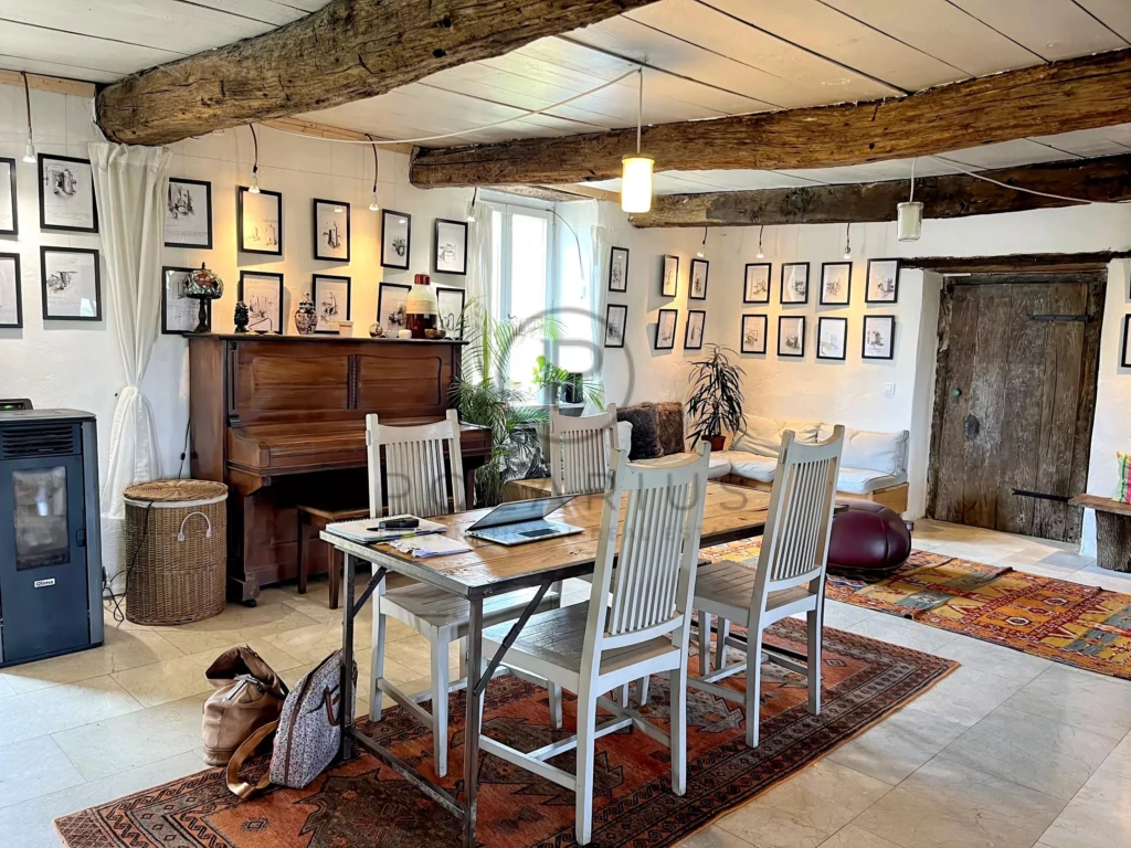 Salle à manger lumineuse avec des poutres en bois apparentes et une décoration chaleureuse.