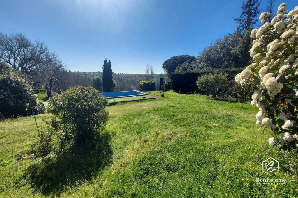 Un grand jardin verdoyant avec une piscine, idéal pour la détente en plein air.