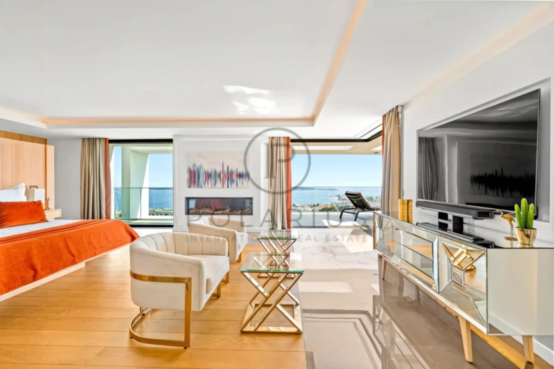 Une chambre moderne et spacieuse avec un lit double, une grande télévision et une vue sur la mer.