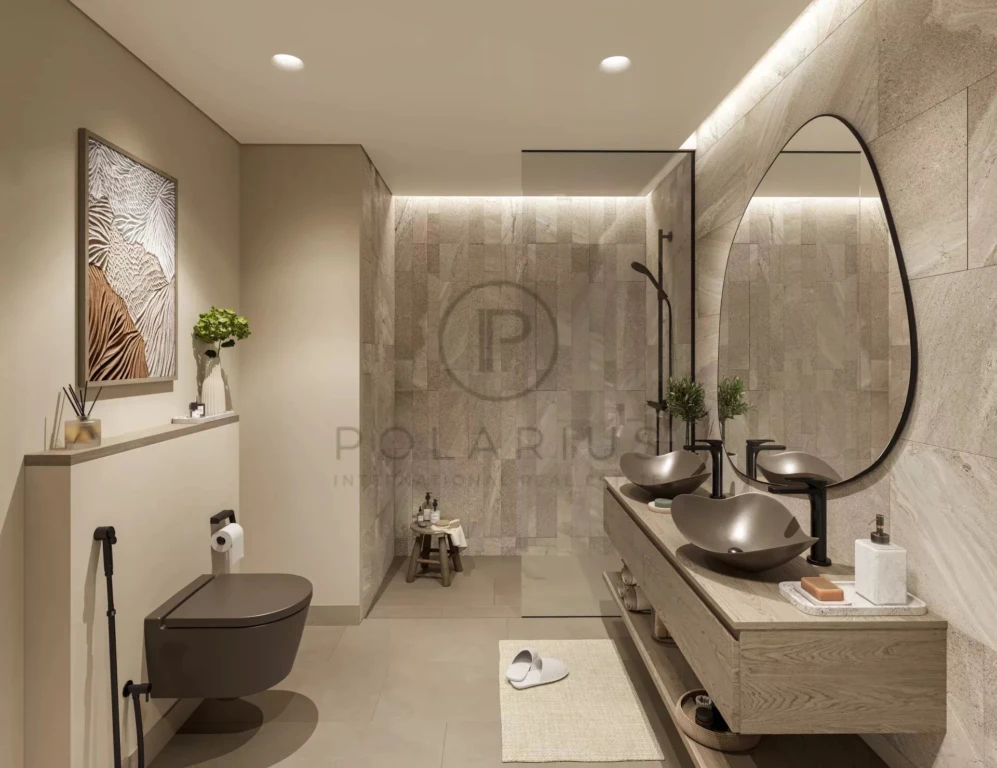 Cette image montre une salle de bain moderne avec des lavabos élégants, un grand miroir ovale, et un design minimaliste.