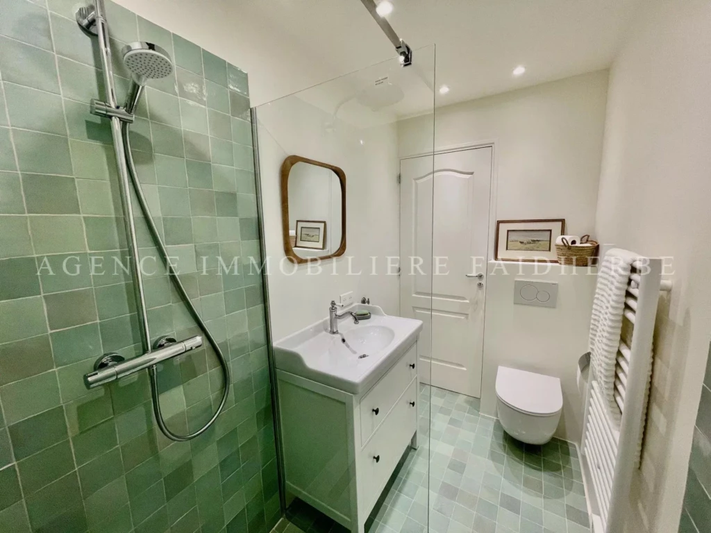 Salle de bain moderne avec douche à l'italienne, lavabo élégant et toilettes suspendues.