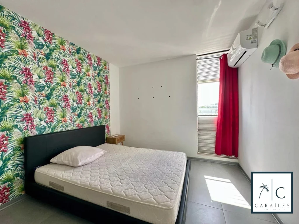 Chambre lumineuse avec mur floral et accès à la climatisation.