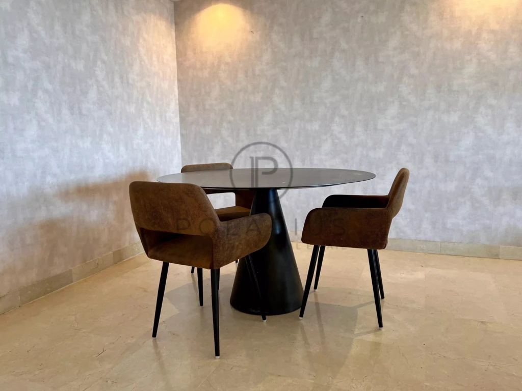Salle à manger moderne avec quatre chaises en tissu brun et une table ronde noire.