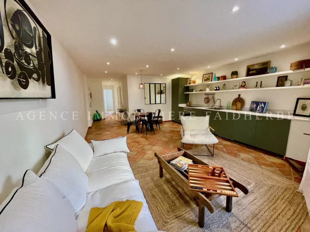 Salon lumineux avec canapé blanc et étagères élégantes dans un appartement moderne.
