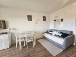 Espace de vie d'un studio meublé à Hyères Port avec coin repas et canapé convertible.