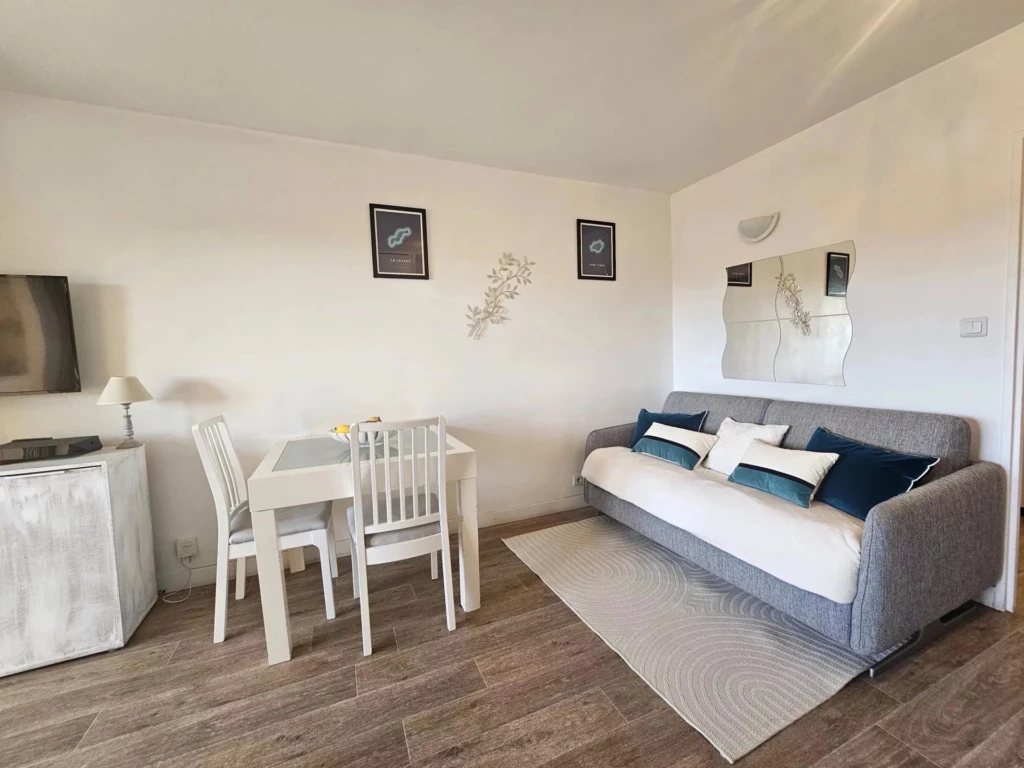 Espace de vie d'un studio meublé à Hyères Port avec coin repas et canapé convertible.