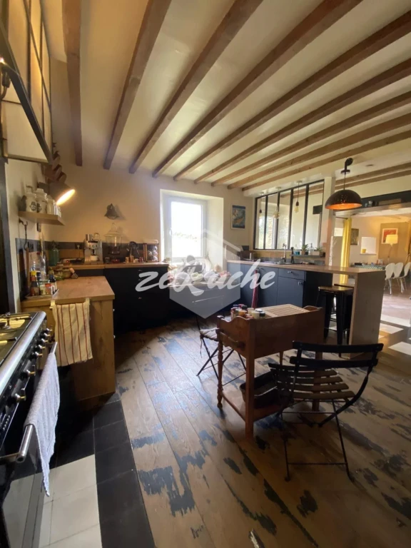 Salon chaleureux avec poutres apparentes et lumière naturelle abondante.