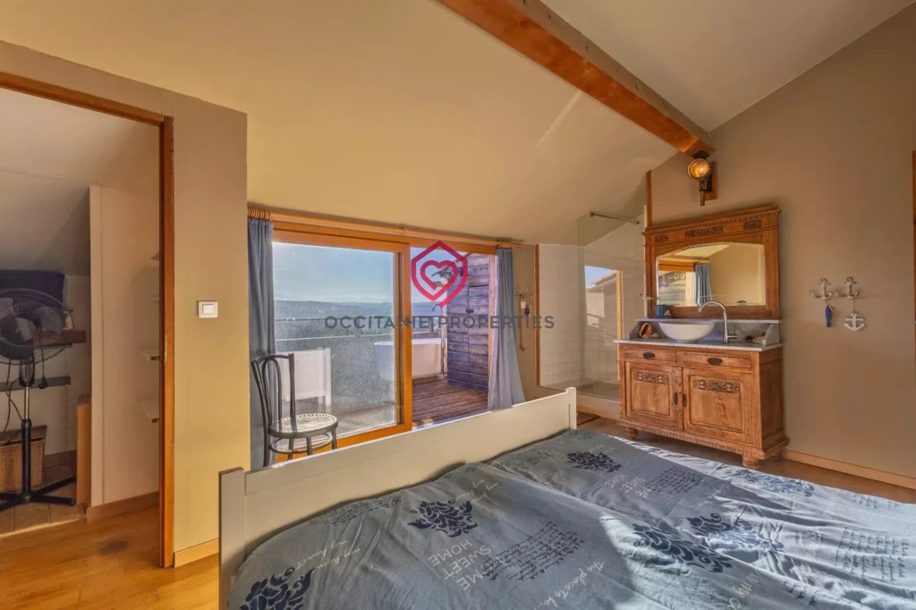 Une chambre lumineuse avec un lit et une commode, donnant sur une terrasse avec vue.