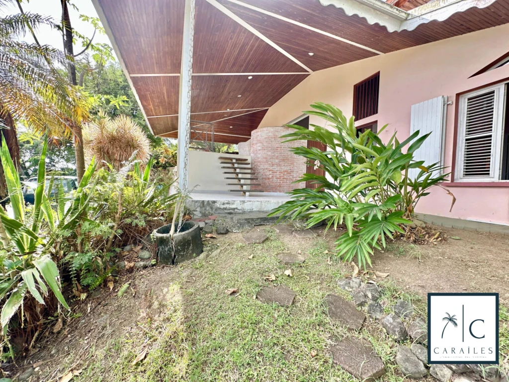 Jardin spacieux et verdoyant devant une maison avec un toit en pente.