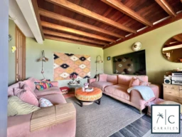 Un salon confortable avec un plafond en bois et des meubles rose poudré.
