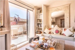 Salon lumineux avec un balcon offrant une vue sur le toit des environs, décoration élégante et confortable.