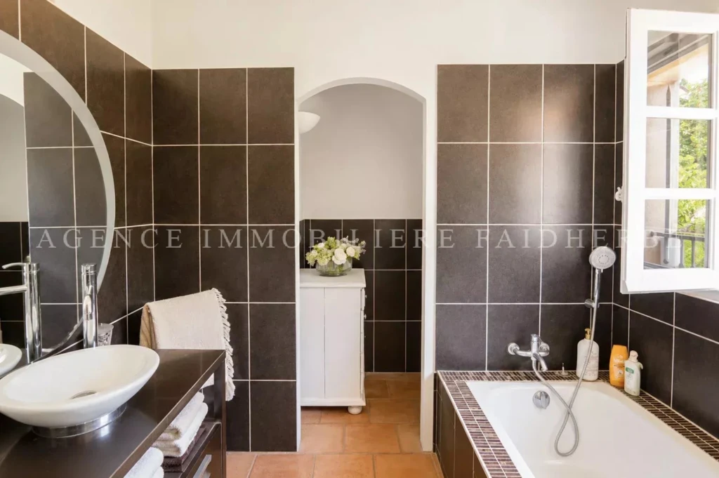 Salle de bain lumineuse avec baignoire et grande fenêtre dans une maison cozy.