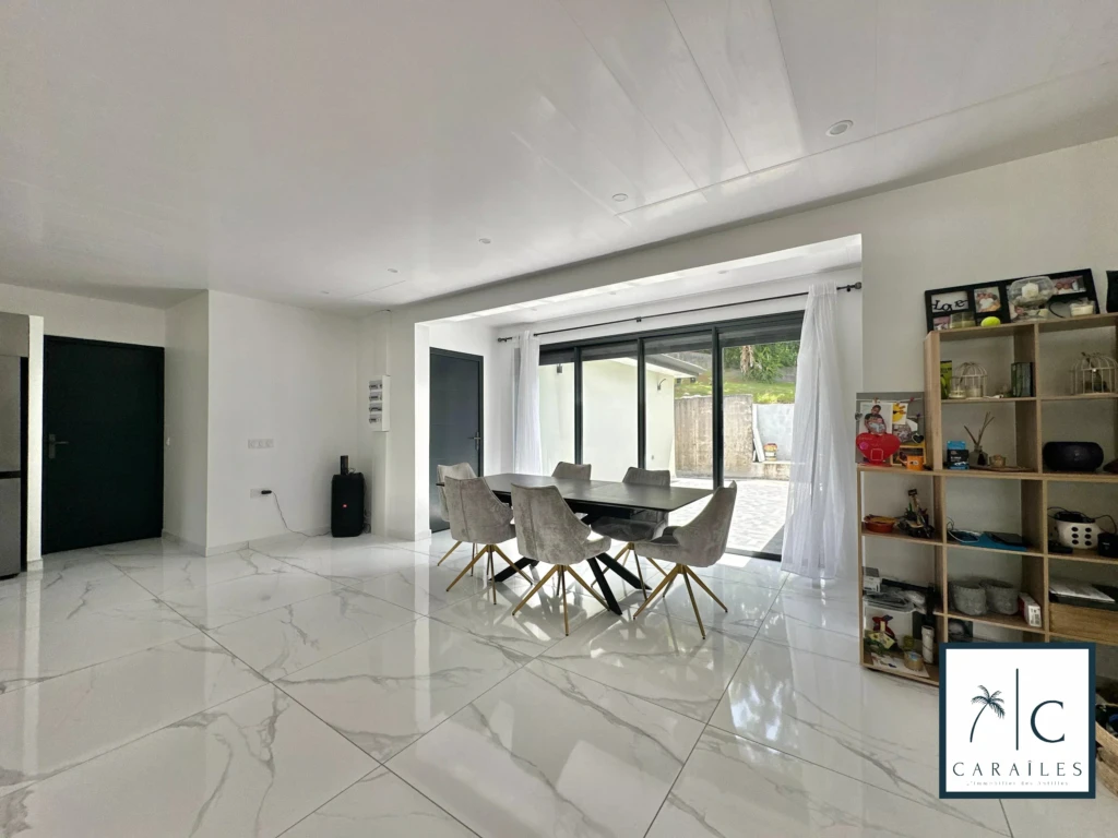 Salle à manger lumineuse avec vue sur l'extérieur et murs blancs modernes.