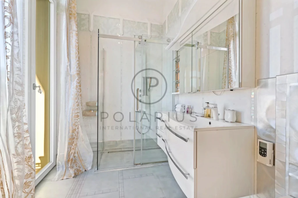 C'est une salle de bain moderne avec une douche en verre et un grand miroir.
