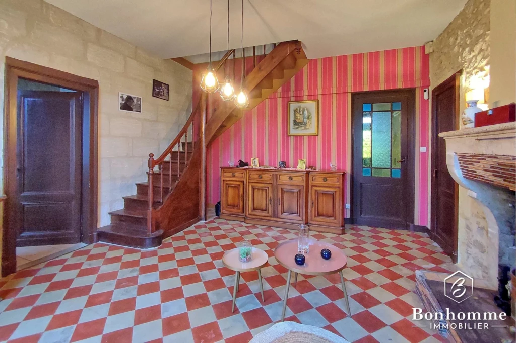 Salon chaleureux avec un sol en carreaux de style ancien et une cheminée en pierre.