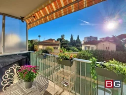 Balcon ensoleillé avec vue sur des maisons et jardins, décoré de plantes en pot.