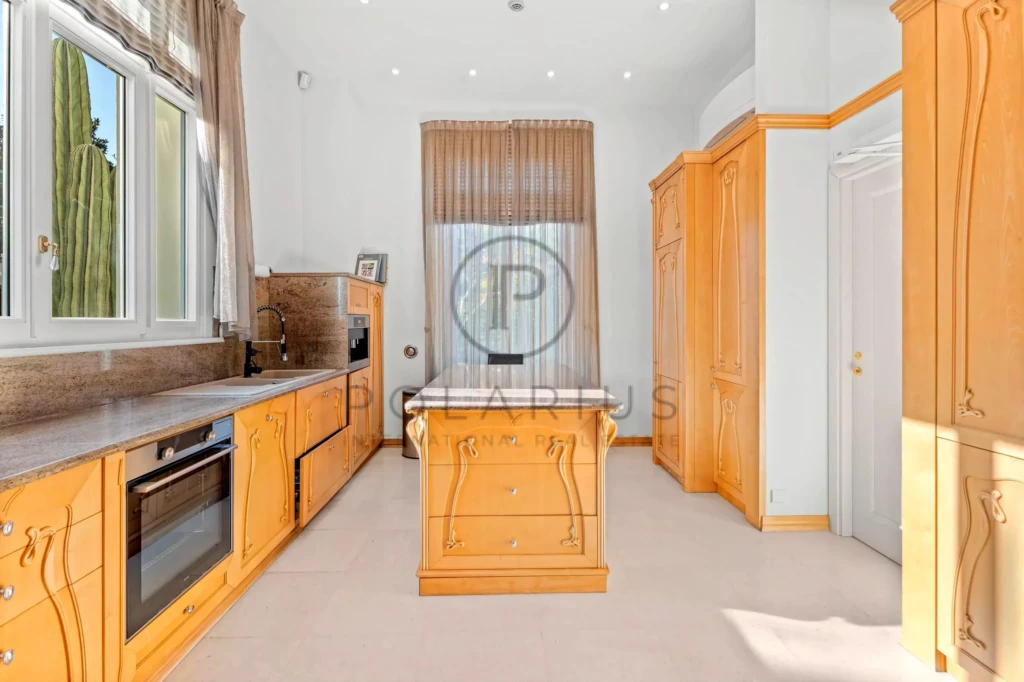 Cuisine lumineuse avec des meubles en bois clair et une grande fenêtre.