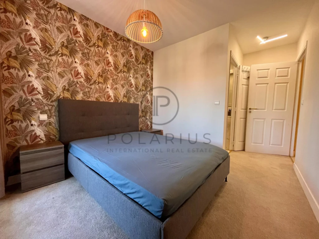 Chambre lumineuse avec un mur accent en papier peint floral et un lit confortable.