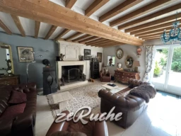 Salon spacieux avec poutres en bois apparentes et cheminée authentique.