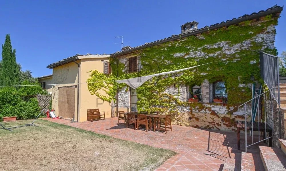 Charmante maison en pierre avec terrasse ensoleillée et jardin verdoyant.