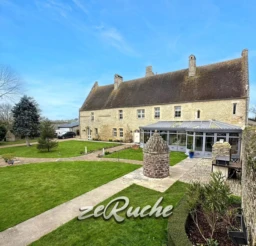 Belle maison en pierre avec jardins spacieux et terrasse ensoleillée.