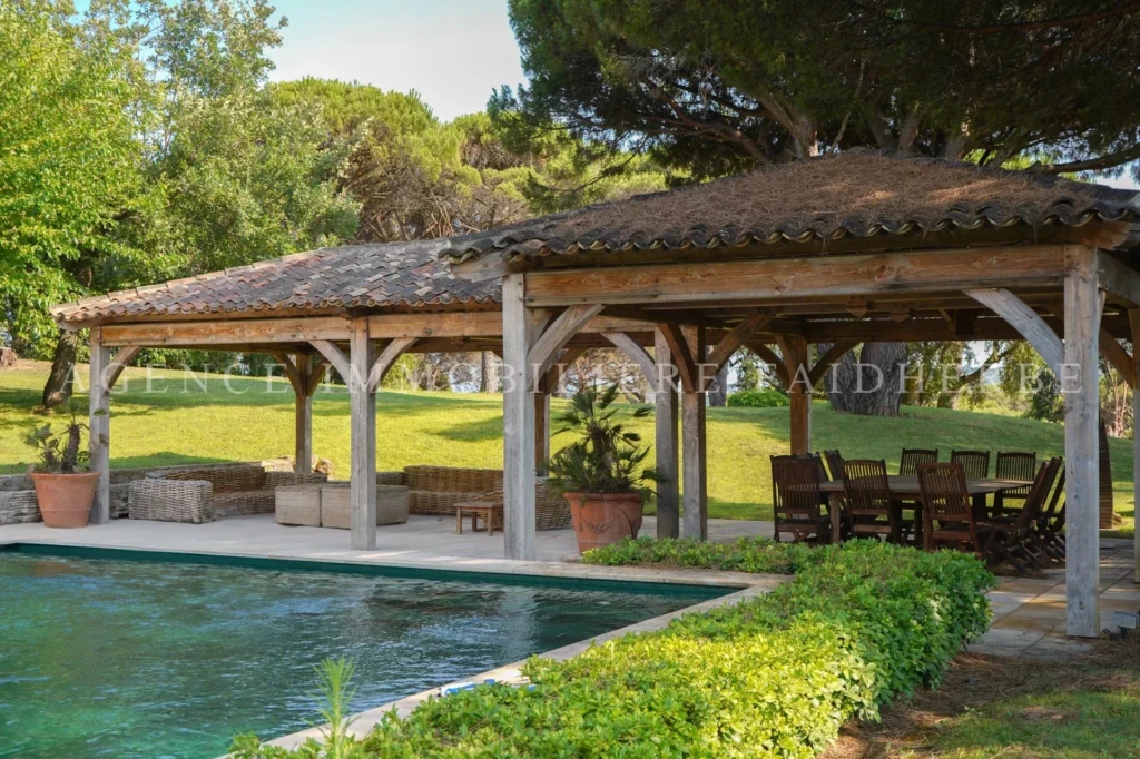 Charmante terrasse ombragée avec vue sur la piscine et le jardin verdoyant.