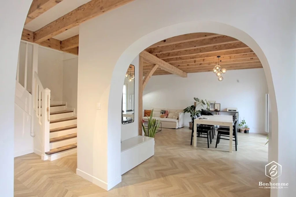 Salon spacieux avec poutres en bois apparentes et décoration moderne.