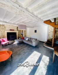Salon spacieux avec un plafond en bois et une cheminée au centre.