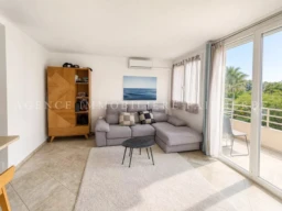 Salon lumineux avec vue sur la mer et accès à un balcon.