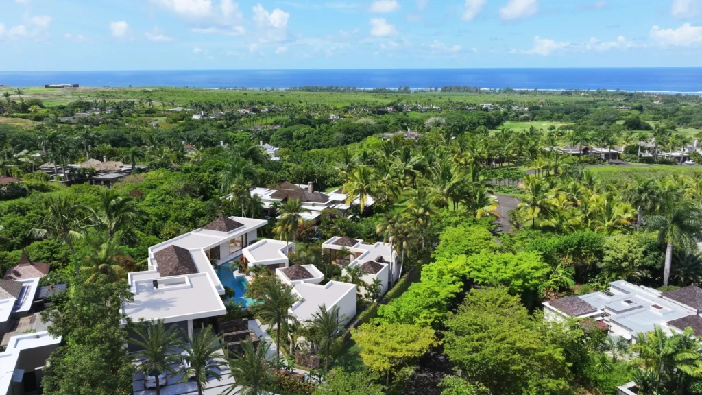 Un aperçu magnifique d'une propriété résidentielle entourée de verdure avec une vue sur l'océan à l'horizon. -Elegance Properties