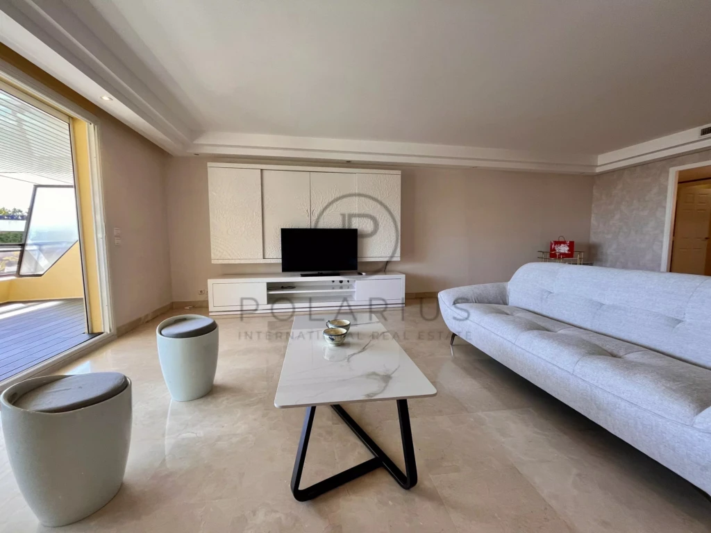 Salon lumineux avec canapé blanc et télévision intégrée dans un espace moderne.