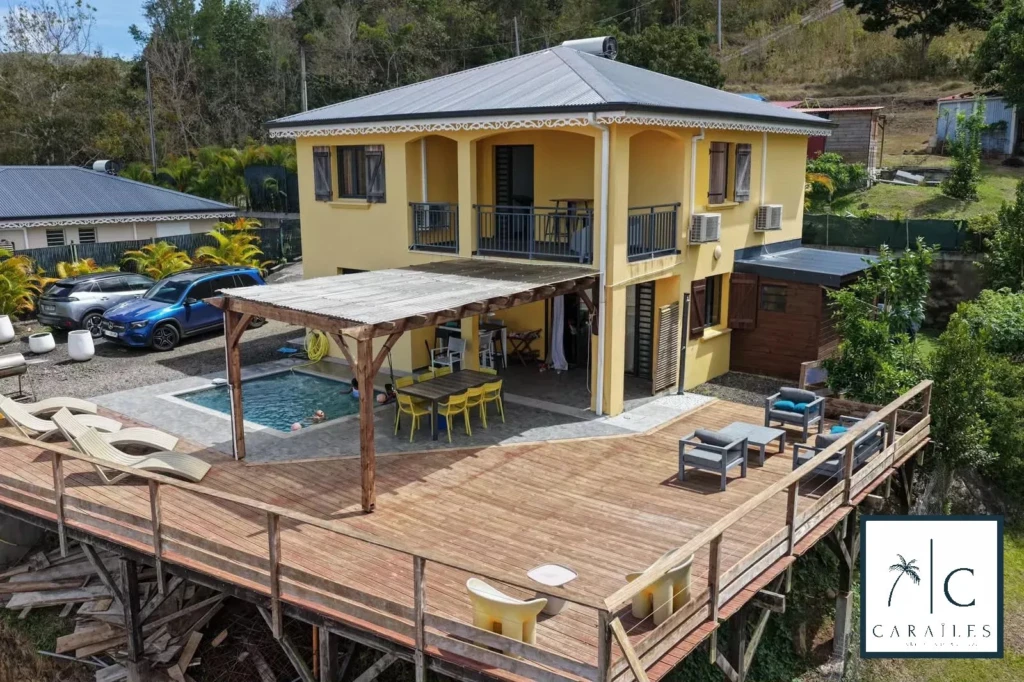 Belle maison avec une grande terrasse en bois et une piscine, idéale pour la détente et les loisirs.