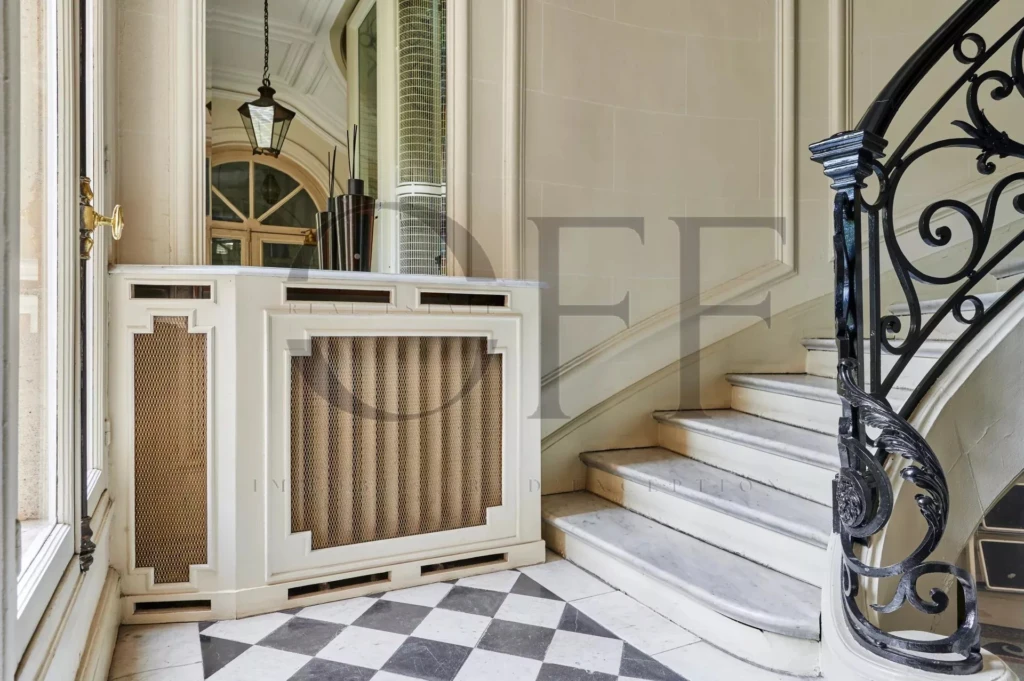 Un élégant hall d'entrée avec un escalier en colimaçon et un sol en damier noir et blanc Paris 7ème Gros caillou.