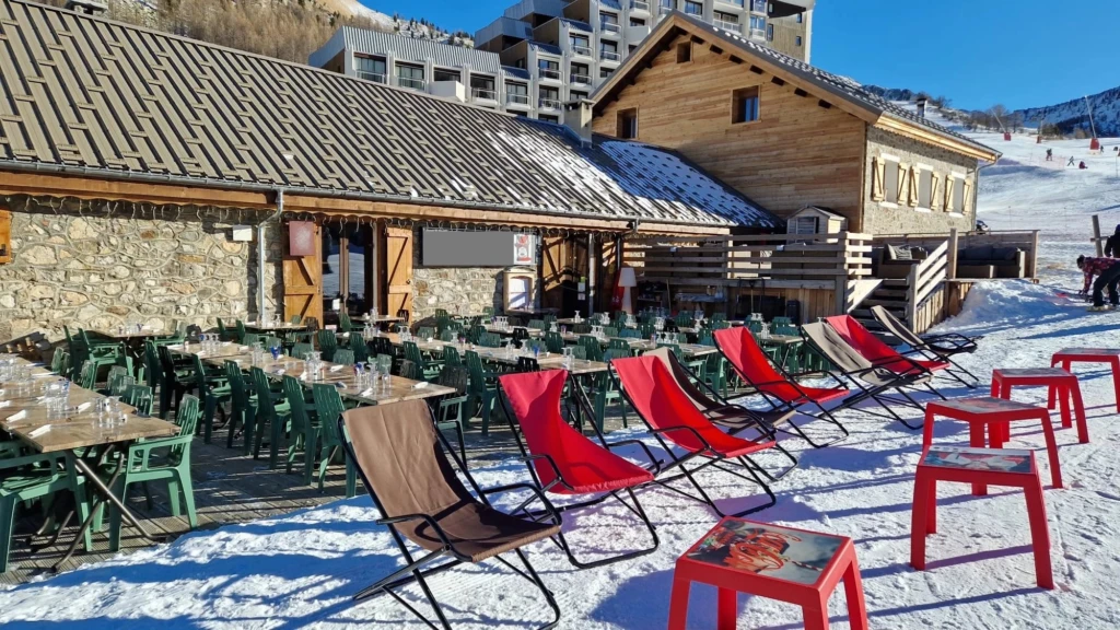 Restaurant avec terrasse ensoleillée et vue sur la montagne.