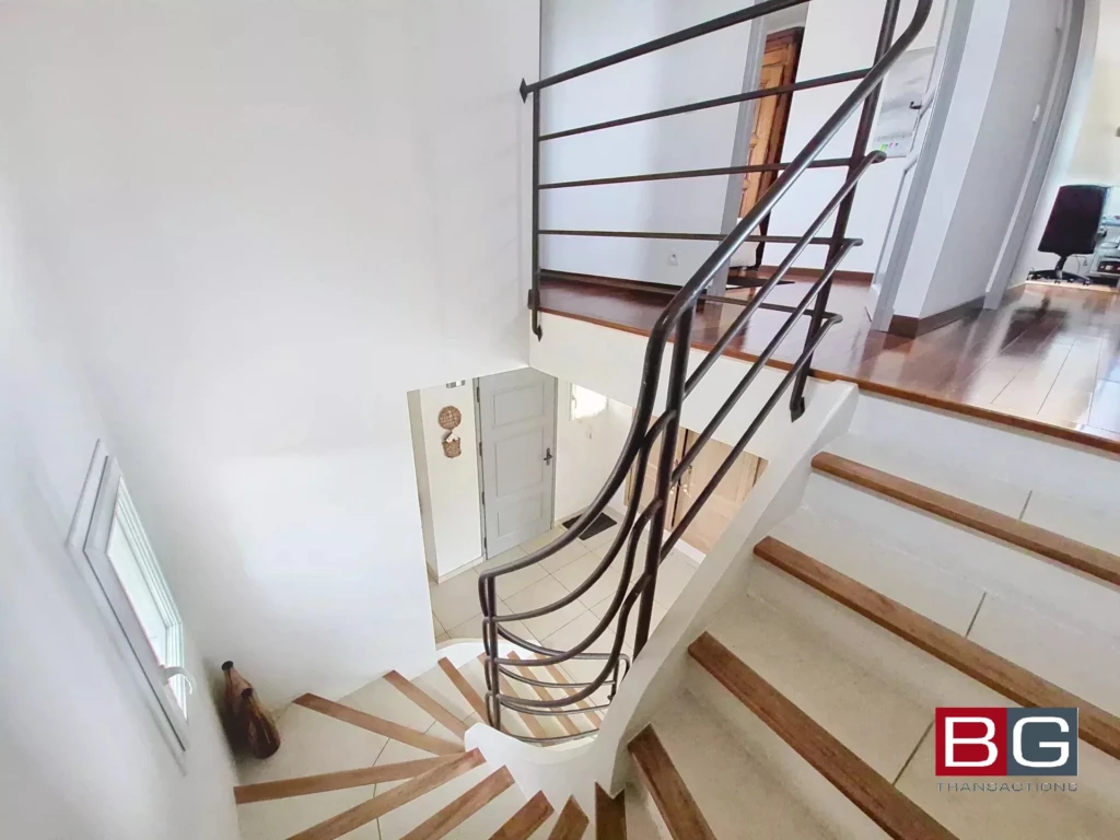 Un escalier moderne en bois et métal dans une maison lumineuse.