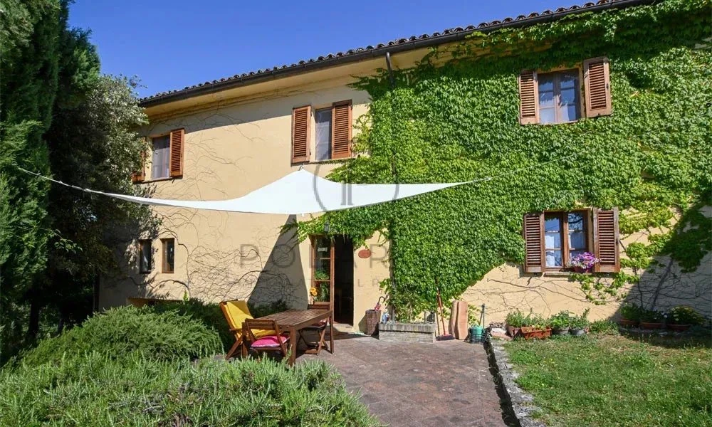 Charmante maison avec façade partiellement couverte de lierre et un jardin accueillant.