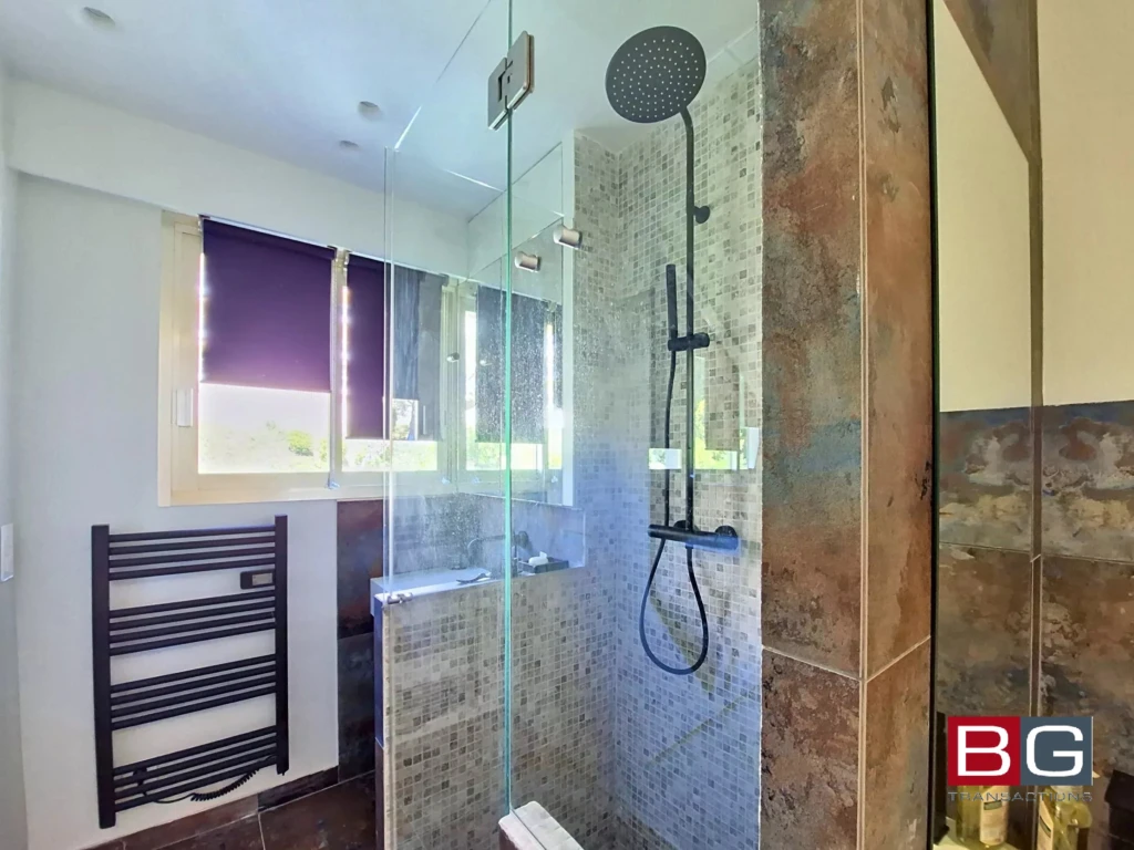 Salle de bain moderne avec douche à l'italienne et fenêtres lumineuses.