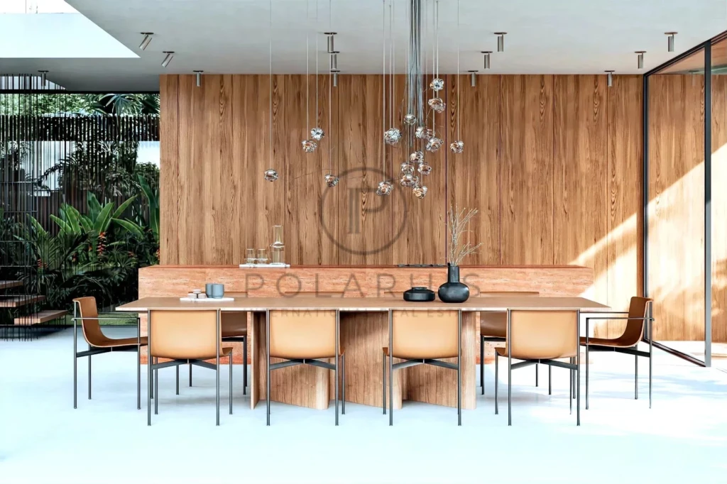 Une salle à manger moderne avec des chaises en cuir brun autour d'une table en bois, des suspensions élégantes et des plantes vertes en arrière-plan.