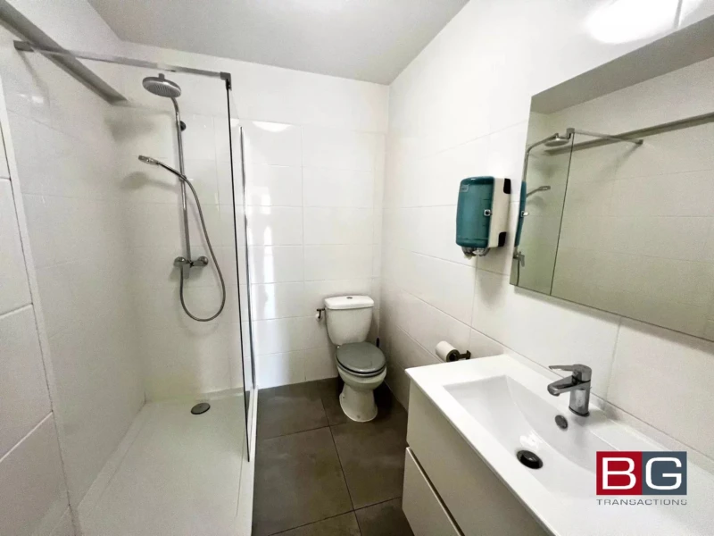 Une salle de bain moderne avec douche, toilettes et lavabo.