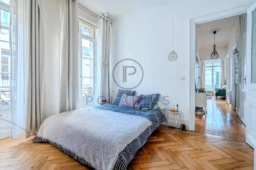 Chambre lumineuse avec parquet en bois et grande fenêtre offrant une vue agréable.