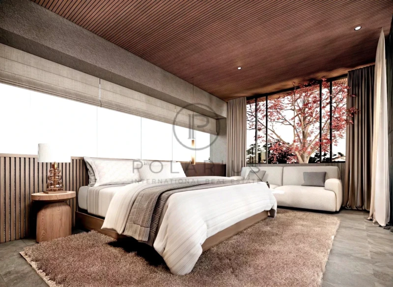 Une chambre moderne avec un grand lit, un plafond en bois, et une grande fenêtre montrant un arbre rouge à l'extérieur.